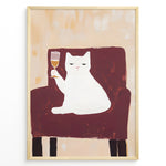 Ladda upp bild till gallerivisning, Funny cat art print plakat showing a white cat sitting on a maroon chair holding a wine glass, framed in black on a beige background.
