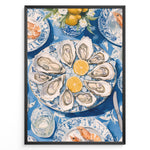 Ladda upp bild till gallerivisning, Oyster platter art print plakat showing oysters and lemon slices on a blue patterned table with seafood dishes and glassware in a black frame.

