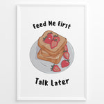 Ladda upp bild till gallerivisning, Funny kitchen poster with a plate of toast and strawberries, and the text “Feed Me First Talk Later,” framed in black on a white background.
