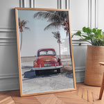 Ladda upp bild till gallerivisning, Plakat med vintage bil | Sommer og Strand Plakater | Denne plakat viser en vintage rød bil parkeret ved en strandvej med havet og palmetræer i baggrunden. Perfekt til dem, der elsker retro og strandstemning.
