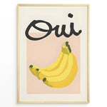 Ladda upp bild till gallerivisning, Modern art poster featuring the word “Oui” in bold black text above a bunch of yellow bananas on a soft pink background, framed as French kitchen wall décor.
