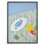 Ladda upp bild till gallerivisning, Mediterranean still life poster with fish on a white plate, lemon, radishes, olives, and a pink drink on a green and white striped tablecloth, framed as kitchen wall art.
