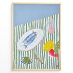 Ladda upp bild till gallerivisning, Mediterranean still life poster with fish on a white plate, lemon, radishes, olives, and a pink drink on a green and white striped tablecloth, framed as kitchen wall art.
