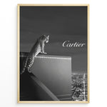 Ladda upp bild till gallerivisning, Fashion Plakat | Cartier Panther Over the City: Iconic Elegance in Monochrome Plakaty.dk | Black and white image of a panther perched on a Cartier box overlooking a city skyline at night, with the Cartier logo in the sky.
