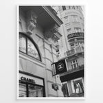 Ladda upp bild till gallerivisning, Fashion Plakat | Chanel Boutique Vienna Black &amp; White Architectural Poster Plakaty.dk | Black and white photo of a Chanel store in a European city with ornate architecture and a Chanel flag sign.
