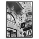 Ladda upp bild till gallerivisning, Fashion Plakat | Chanel Boutique Vienna Black &amp; White Architectural Poster Plakaty.dk | Black and white photo of a Chanel store in a European city with ornate architecture and a Chanel flag sign.
