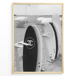 Ladda upp bild till gallerivisning, Fashion Plakat | Chanel Surfboards on the Beach – Luxury Meets Coastal Lifestyle in Black and White Plakaty.dk | Black and white photo of Chanel and J12 Yacht Club surfboards on a sandy beach with umbrellas and lounge chairs in the background
