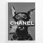Ladda upp bild till gallerivisning, Fashion Plakat | Edgy Chanel-Inspired Art Featuring Dog with Gun Plakaty.dk | Black dog with spiked collar holding a handgun in its mouth, with the word &quot;CHANEL&quot; overlaid in bold white text.
