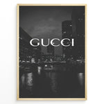 Ladda upp bild till gallerivisning, Fashion Plakat | Gucci Cityscape Black &amp; White Fashion Poster Plakaty.dk | Black and white poster with the Gucci logo over a night cityscape featuring tall buildings and water reflections.
