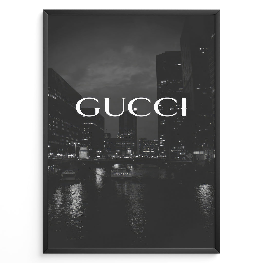 Fashion Plakat | Gucci Cityscape Black & White Fashion Poster Plakaty.dk | Black and white poster with the Gucci logo over a night cityscape featuring tall buildings and water reflections.