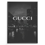 Ladda upp bild till gallerivisning, Fashion Plakat | Gucci Cityscape Black &amp; White Fashion Poster Plakaty.dk | Black and white poster with the Gucci logo over a night cityscape featuring tall buildings and water reflections.
