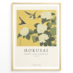 Ladda upp bild till gallerivisning, Japanske plakater | Japanese woodblock print of white trumpet lilies with green leaves and two sparrows flying against a yellow background, based on Hokusai’s  floral artwork.
