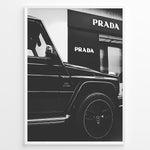 Ladda upp bild till gallerivisning, Fashion Plakat | Mercedes-Benz G-Wagon and Prada Store Black and White Art Print Plakaty.dk | A framed, black and white photograph showing the side profile of a Mercedes-Benz G-Wagon AMG parked in front of a Prada store. The car&#39;s V8 BITURBO badge is visible, and the Prada logo is prominent on the building&#39;s facade.
