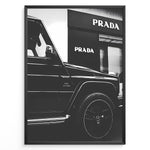 Ladda upp bild till gallerivisning, Fashion Plakat | Mercedes-Benz G-Wagon and Prada Store Black and White Art Print Plakaty.dk | A framed, black and white photograph showing the side profile of a Mercedes-Benz G-Wagon AMG parked in front of a Prada store. The car&#39;s V8 BITURBO badge is visible, and the Prada logo is prominent on the building&#39;s facade.
