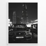 Ladda upp bild till gallerivisning, Fashion Plakat | Midnight Luxury – Brabus G-Wagon in Dubai Plakaty.dk | Black and white photo of a Brabus G-Wagon parked in front of the Dubai skyline at night, with skyscrapers like Burj Khalifa and EMAAR towers in the background.
