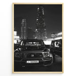 Ladda upp bild till gallerivisning, Fashion Plakat | Midnight Luxury – Brabus G-Wagon in Dubai Plakaty.dk | Black and white photo of a Brabus G-Wagon parked in front of the Dubai skyline at night, with skyscrapers like Burj Khalifa and EMAAR towers in the background.
