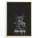 Ladda upp bild till gallerivisning, Fashion Plakat | Prada-Inspired Art Featuring Fierce Dog with Gun Plakaty.dk | Black Doberman with a studded collar holding a handgun in its mouth, set against a dark background with the word &quot;PRADA&quot; in bold white text.
